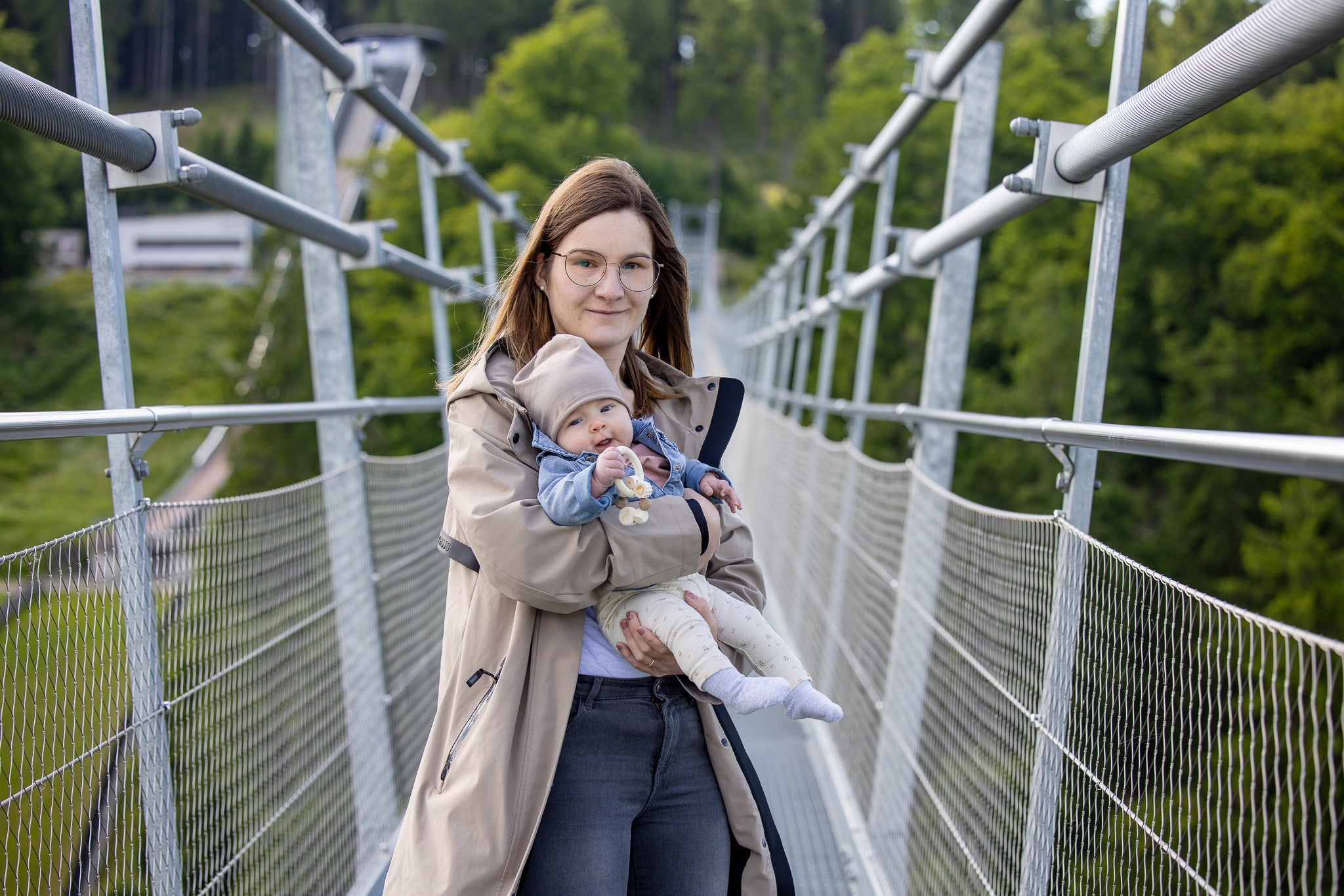 Bild: Eine Mutter mit einem kleinen Baby stehen auf der Brücke. Das Baby hält den Greifring in der Hand.