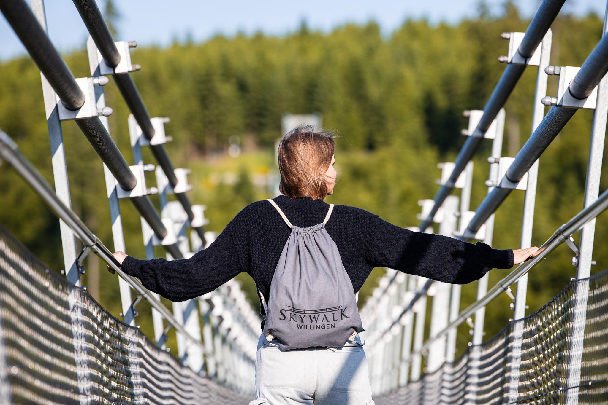 Bild: Es zeigt eine junge Frau auf dem Skywalk-Willingen mit dem Festivalbeutel auf dem Rücken.